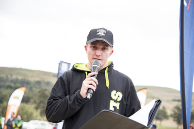 The MC for the day, Mark Mackenzie welcoming home all the athletes as they reach the finish of the trail run - (c) Andrew Mc Fadden / BOOGS Photography